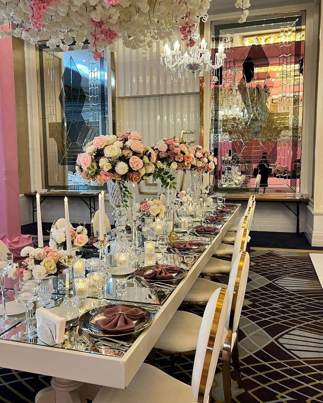 Long mirrored table dressed with blush roses and gold place settings