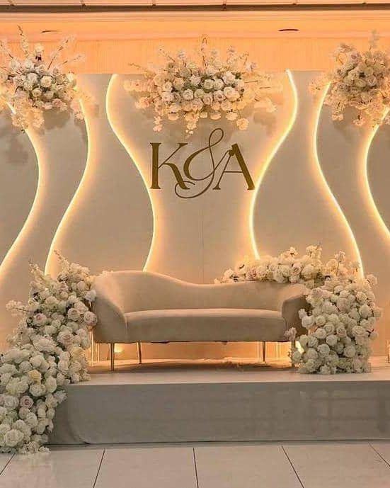 Sculptural lit backdrop with monogram signage and a tiered cake display
