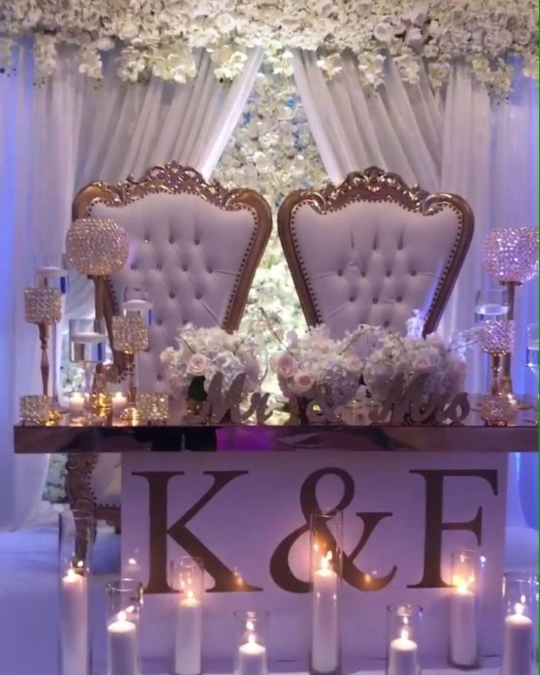 Sweetheart chairs with monogram signage and a candle-lit table