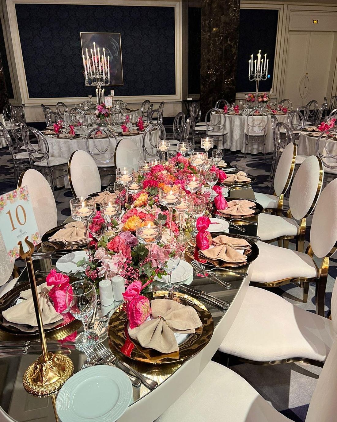 Long reception table with pink and coral florals under a marquee tent